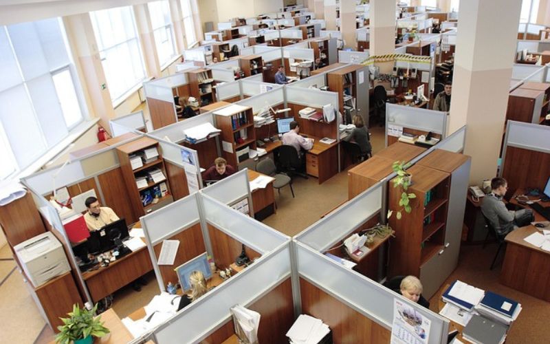 Espacio de oficina amplio separado en cubículos, sin puertas, con poca intimidad y muy sobrecargado.